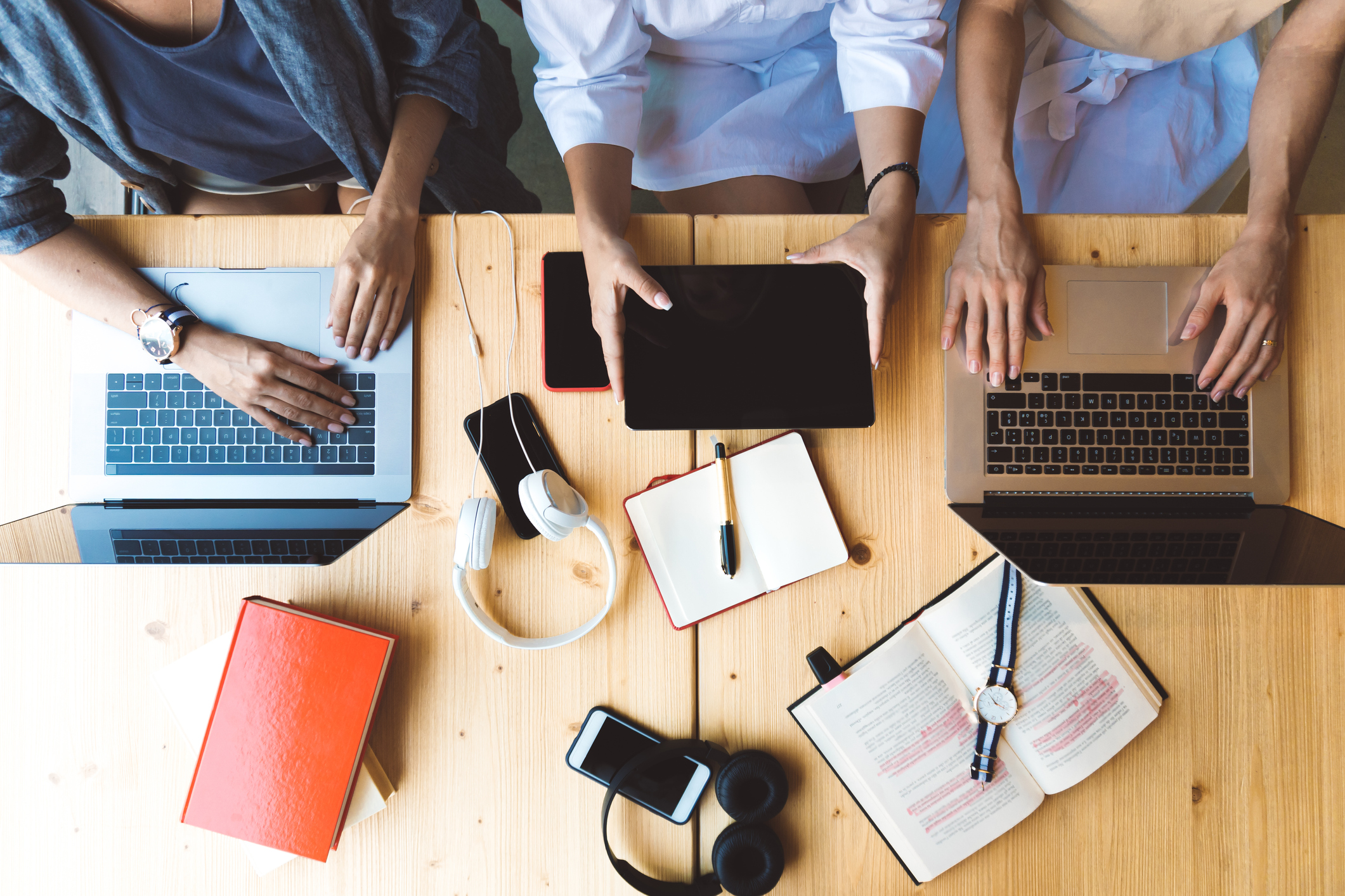 Flat lay picture of three women working with laptops and books sitting at the table together - business woman, co-working and college girls studying concept